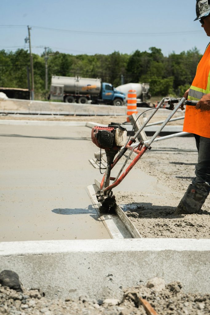 a-man-in-an-orange-safety-vest-is-working-on-a-road-oyx0hxwmpny