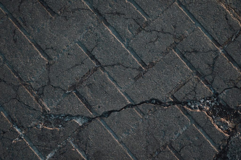 Close-up view of cracked urban pavement showing detailed texture and surface damage.