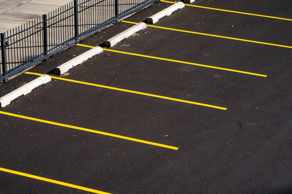 Top view of an empty parking lot with yellow lines and a metal fence, perfect for urban scenes.