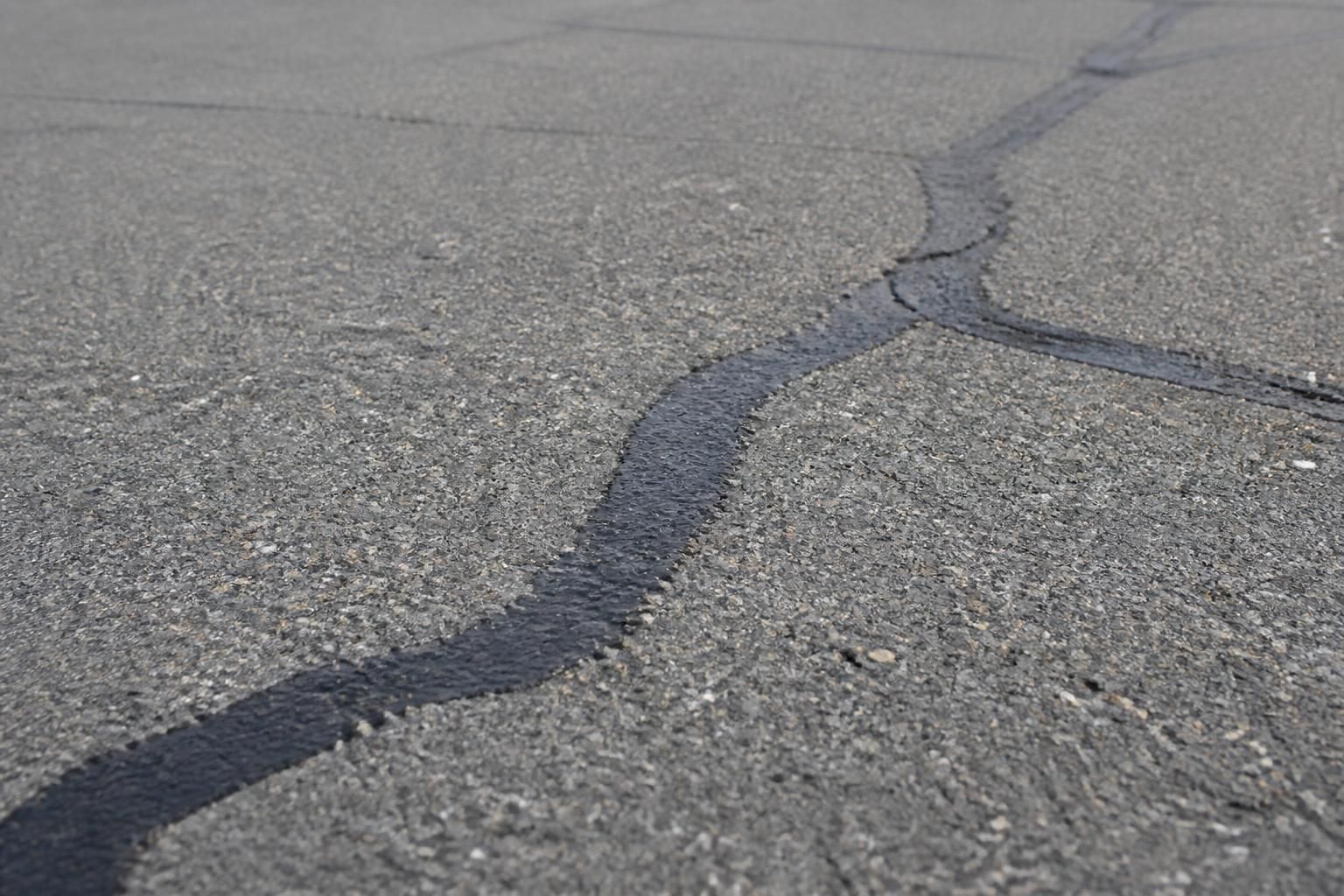 Filled cracks on a finished asphalt pavement surface.